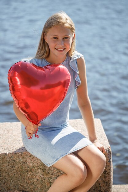 Hermosa joven con un vestido azul con un globo en forma de corazón