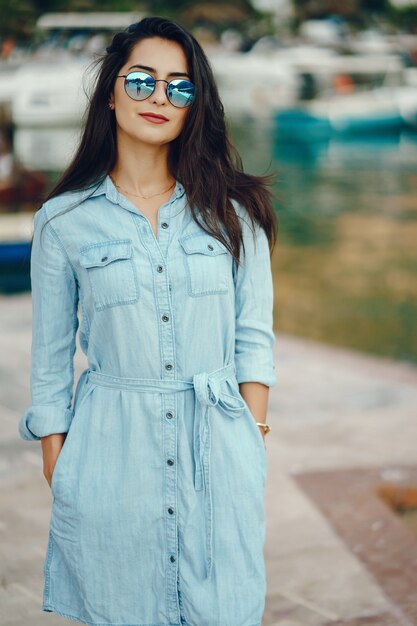 Una hermosa joven en un vestido azul de pie cerca del agua