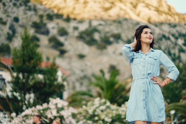 Una hermosa joven en un vestido azul de pie cerca del árbol de flores