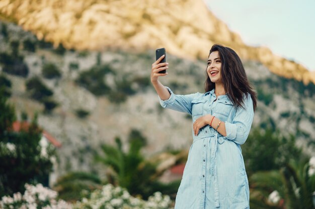 Una hermosa joven con un vestido azul sentado cerca del árbol de flores