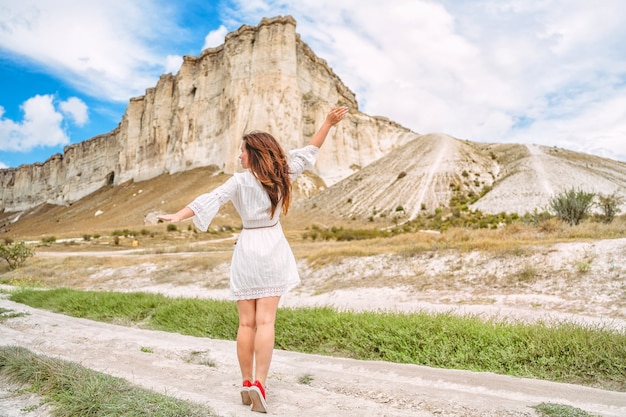 Una hermosa joven con un vestido blanco al pie de una roca blanca en Crimea