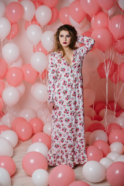 Hermosa joven en un vestido entre un montón de bolas de color rosa.