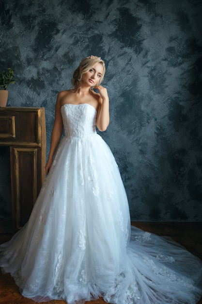 Hermosa joven en vestido de novia, hermosa novia con maquillaje y peinado