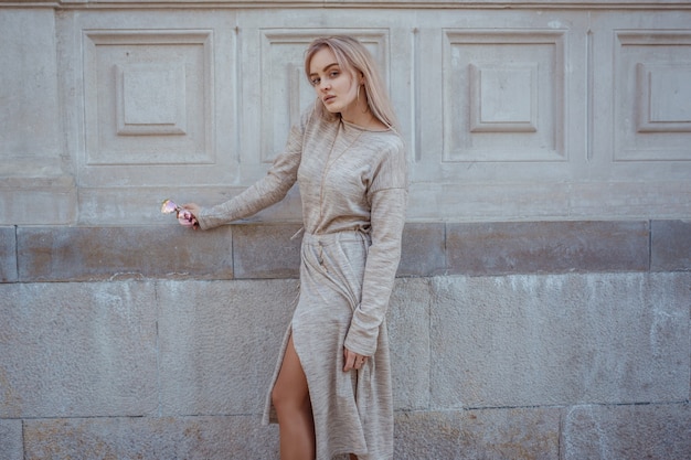 Hermosa joven con un vestido de punto beige camina por las calles de Moscú, un clima soleado de primavera