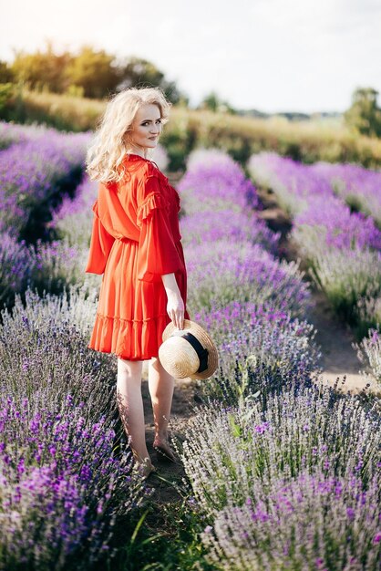 Hermosa joven con un vestido rojo en un campo de lavanda