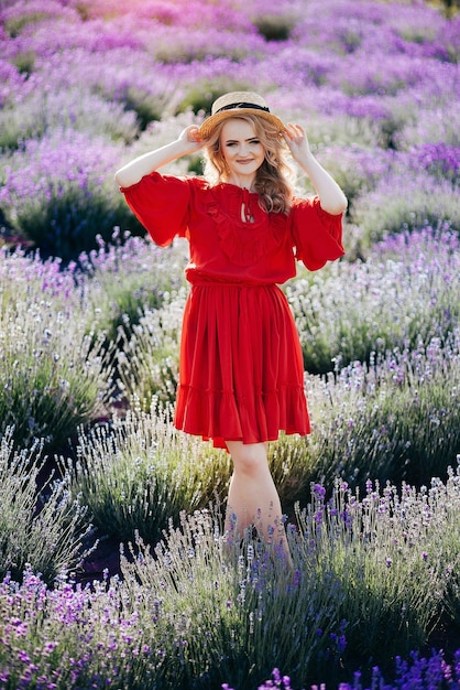 Hermosa joven con un vestido rojo en un campo de lavanda