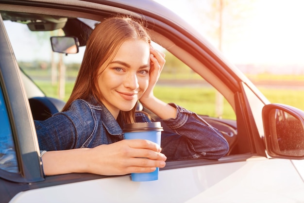 Hermosa joven viajó por carretera en coche bebiendo café de desechables