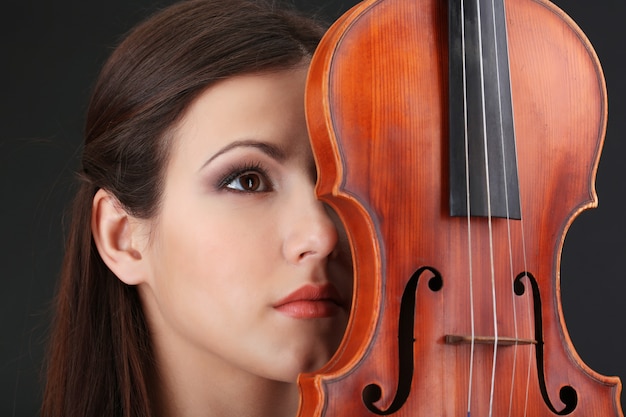 Hermosa joven con violín sobre fondo gris