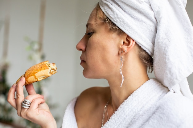 Hermosa joven vistiendo bata blanca desayunando rituales matutinos