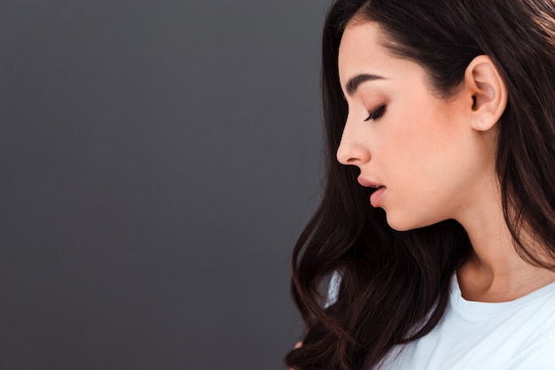 Hermosa joven vistiendo camiseta de pie sobre la superficie aislada gris mirando hacia el lado, relajarse perfil pose con rostro natural