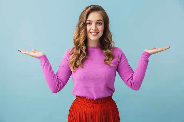 Hermosa joven vistiendo ropa casual que se encuentran aisladas sobre la pared azul, presentando espacio de copia