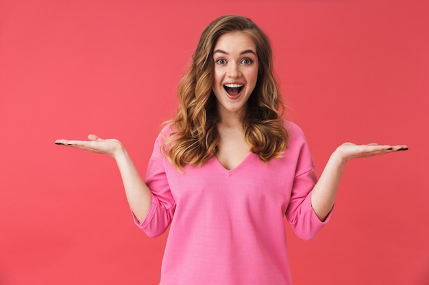 Hermosa joven vistiendo ropa casual que se encuentran aisladas sobre pared rosa, presentando espacio de copia