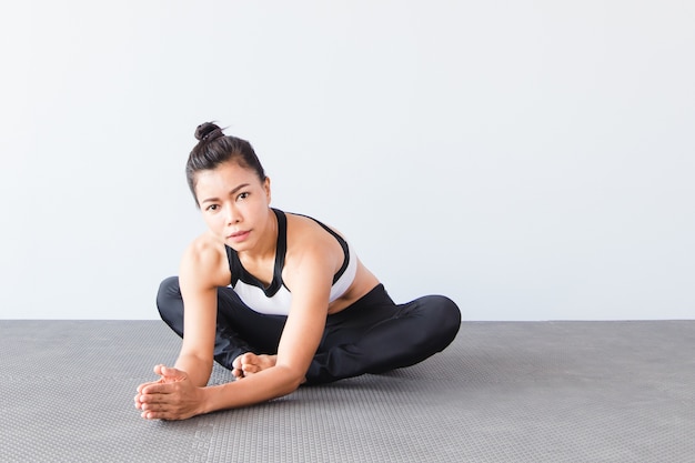 Hermosa joven vistiendo ropa deportiva practicando yoga en estudio