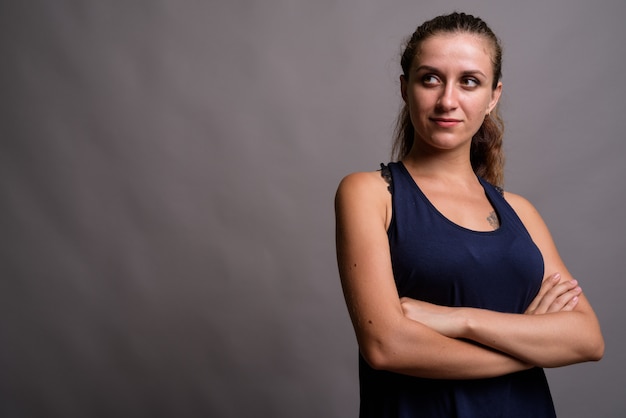 Hermosa joven vistiendo un vestido sin mangas azul sobre gris