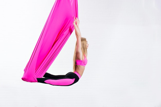 Foto hermosa joven yoga antigravedad en una hamaca de seda rosa mientras se hace.