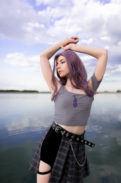 Hermosa jovencita con cabello morado sobre un fondo de nubes