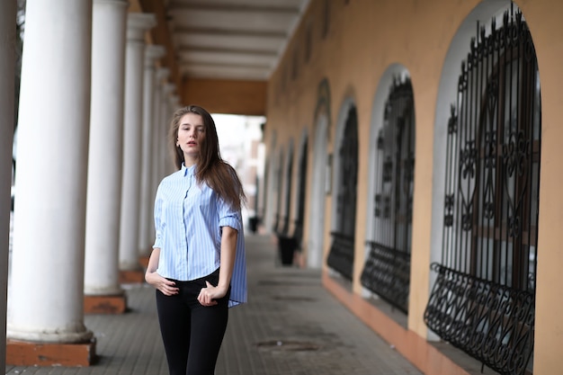 Hermosa jovencita en un paseo cerca de un edificio con una columna