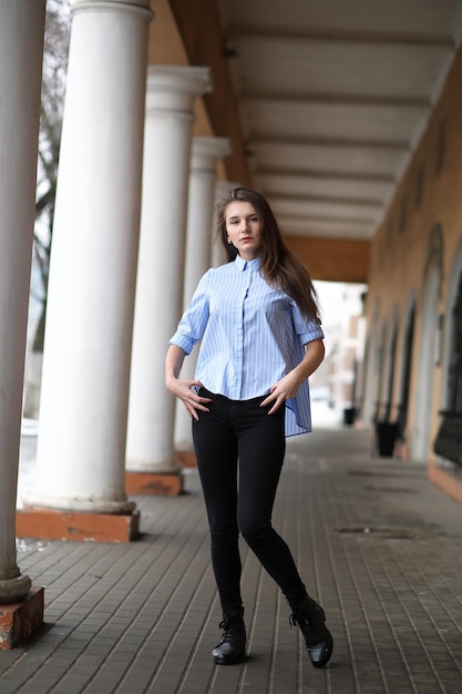 Hermosa jovencita en un paseo cerca de un edificio con una columna