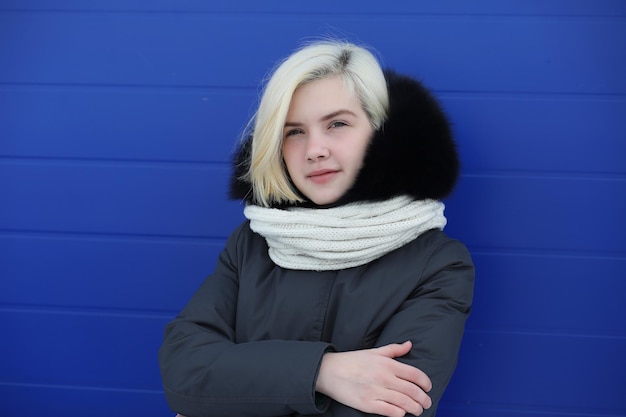 Hermosa jovencita en un paseo en invierno en el fondo de la pared azul