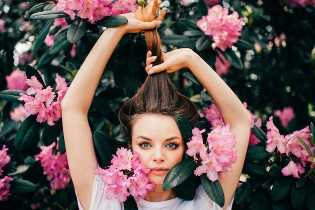 Hermosa jovencita posando entre el árbol en flor