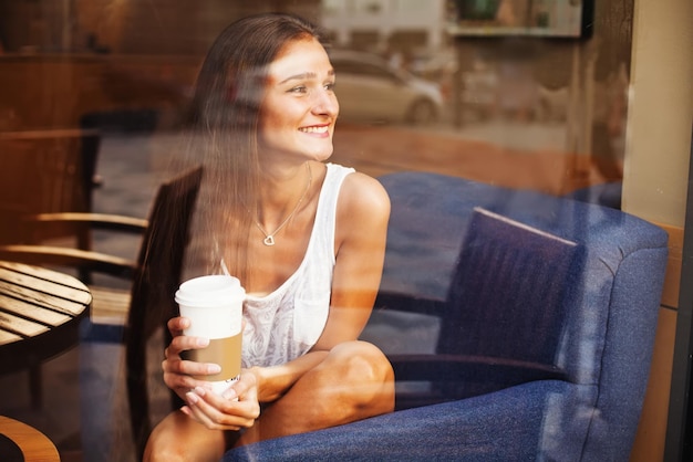 Hermosa jovencita tomando café o té en la cafetería