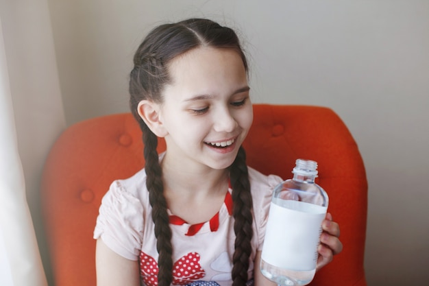 Hermosa jovencita con trenzas con una botella de agua.