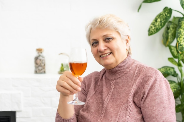 Hermosa linda anciana bebiendo vino de cerca.