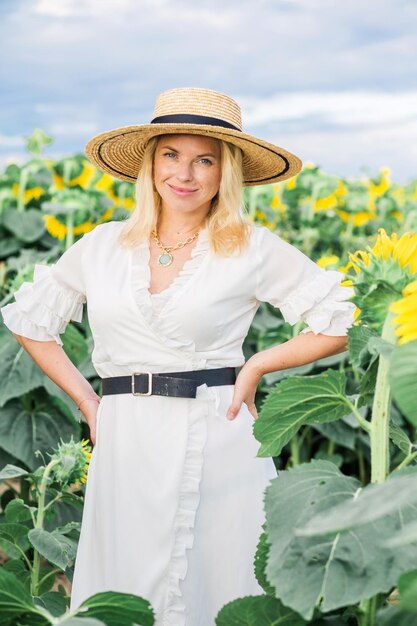 Hermosa linda chica sexy con un vestido blanco camina por el campo de girasoles