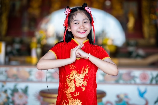 Hermosa linda joven asiática vestida de rojo cheongsam chino tradicional, soporte para rezar a la estatua de Buda para el Festival del Año Nuevo Chino en el santuario chino