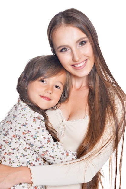 Hermosa madre abraza a su hija sobre un fondo blanco.