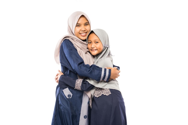 Hermosa madre asiática con hija vistiendo ropa islámica tradicional sobre fondo blanco.