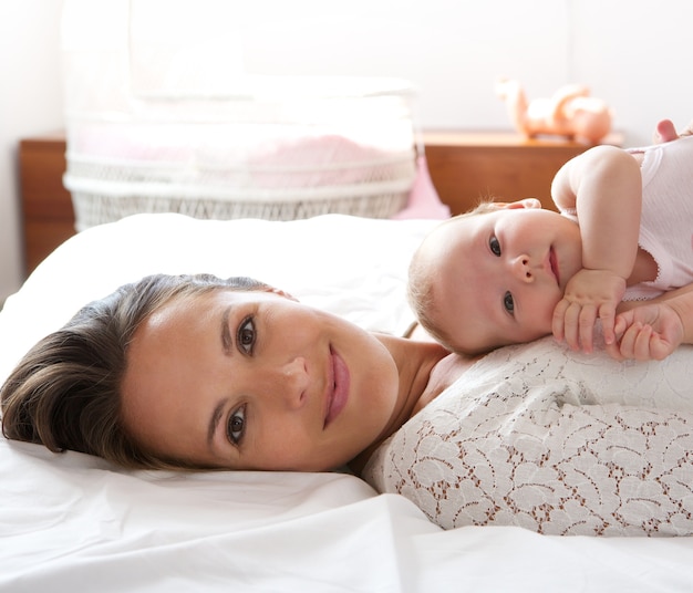 Hermosa madre descansa en la cama con bebé hija