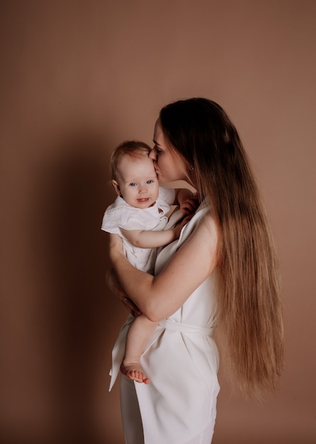 Hermosa madre e hija bebé sobre un fondo beige con un lugar para el texto