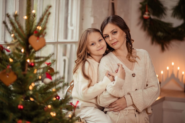 Hermosa madre e hija cerca del árbol de Navidad