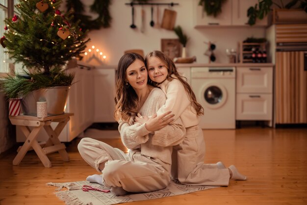 Hermosa madre e hija cerca del árbol de Navidad