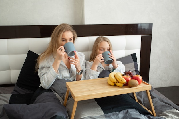 Hermosa madre e hija comiendo en la cama