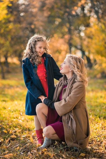 Hermosa madre e hija en otoño colorido al aire libre