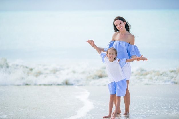 Hermosa madre e hija en la playa caribeña disfrutando de las vacaciones de verano.