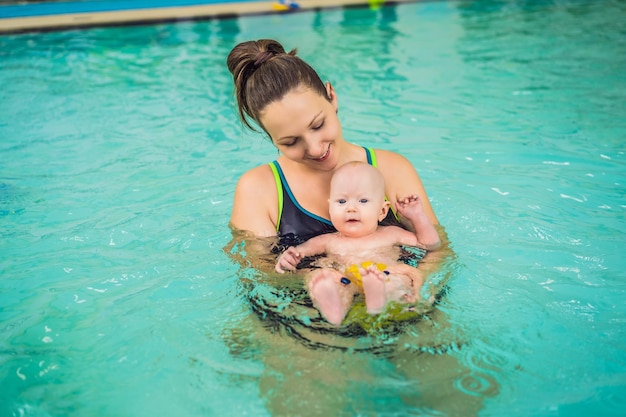 Hermosa madre enseñando a una linda niña a nadar en una piscina Niño divirtiéndose en el agua con mamá