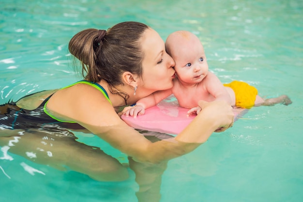 Hermosa madre enseñando a una linda niña a nadar en una piscina Niño divirtiéndose en el agua con mamá