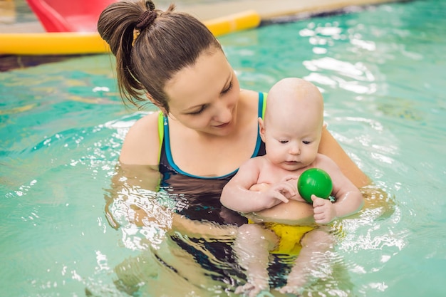 Hermosa madre enseñando a una linda niña a nadar en una piscina Niño divirtiéndose en el agua con mamá