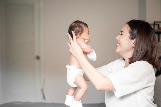 Hermosa madre está jugando con su bebé recién nacido en el dormitorio.