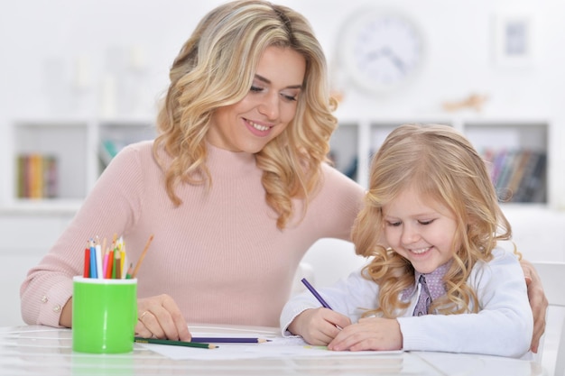 Hermosa madre con hija dibujando con lápices de colores