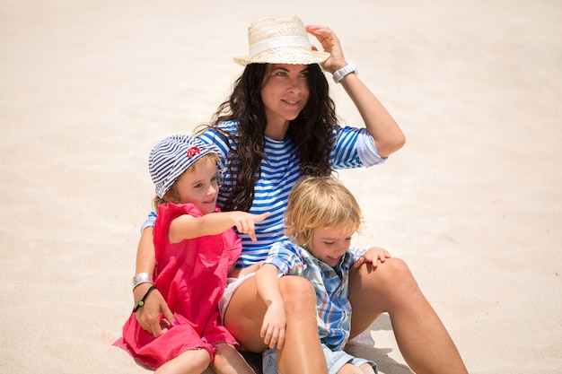 Hermosa madre, hijo e hija sentada en el océano.