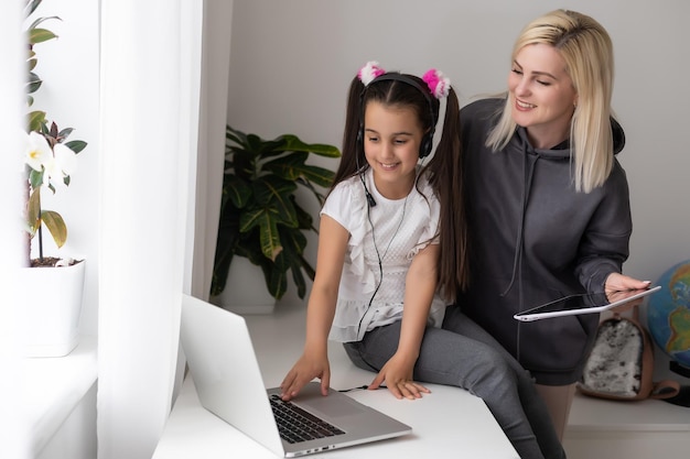 Una hermosa madre joven ayudando a su hija menor con la tarea.