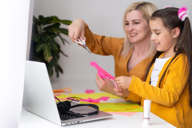 Una hermosa madre joven ayudando a su hija menor con la tarea.