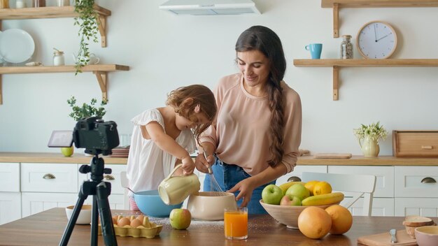 Foto una hermosa madre con una linda hija grabando un blog sobre cocina video blog sobre comida saludable am