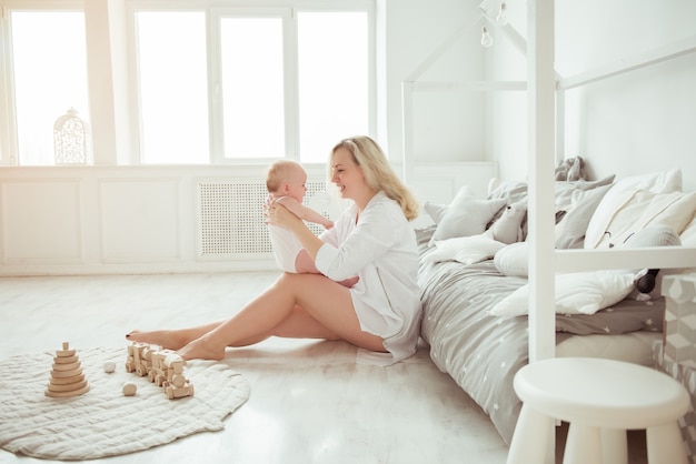 Hermosa madre con un lindo bebé caricias en el dormitorio