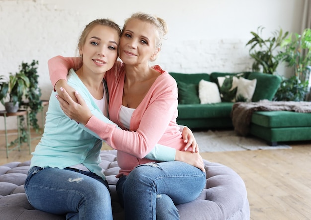 Hermosa madre mayor y su hija adulta se abrazan mirando a la cámara y sonriendo