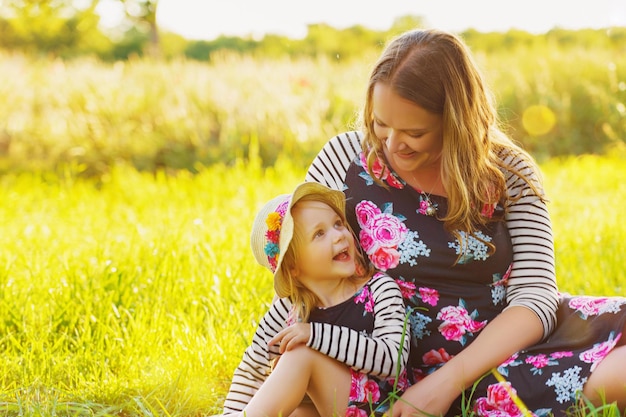 Hermosa madre y niña con hojas otoñales al aire libre